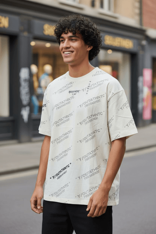 Camisa blanca Y/out de algodón con estampado repetido de logotipos en negro, estilo urbano y moderno ideal para outfits casuales y cómodos.